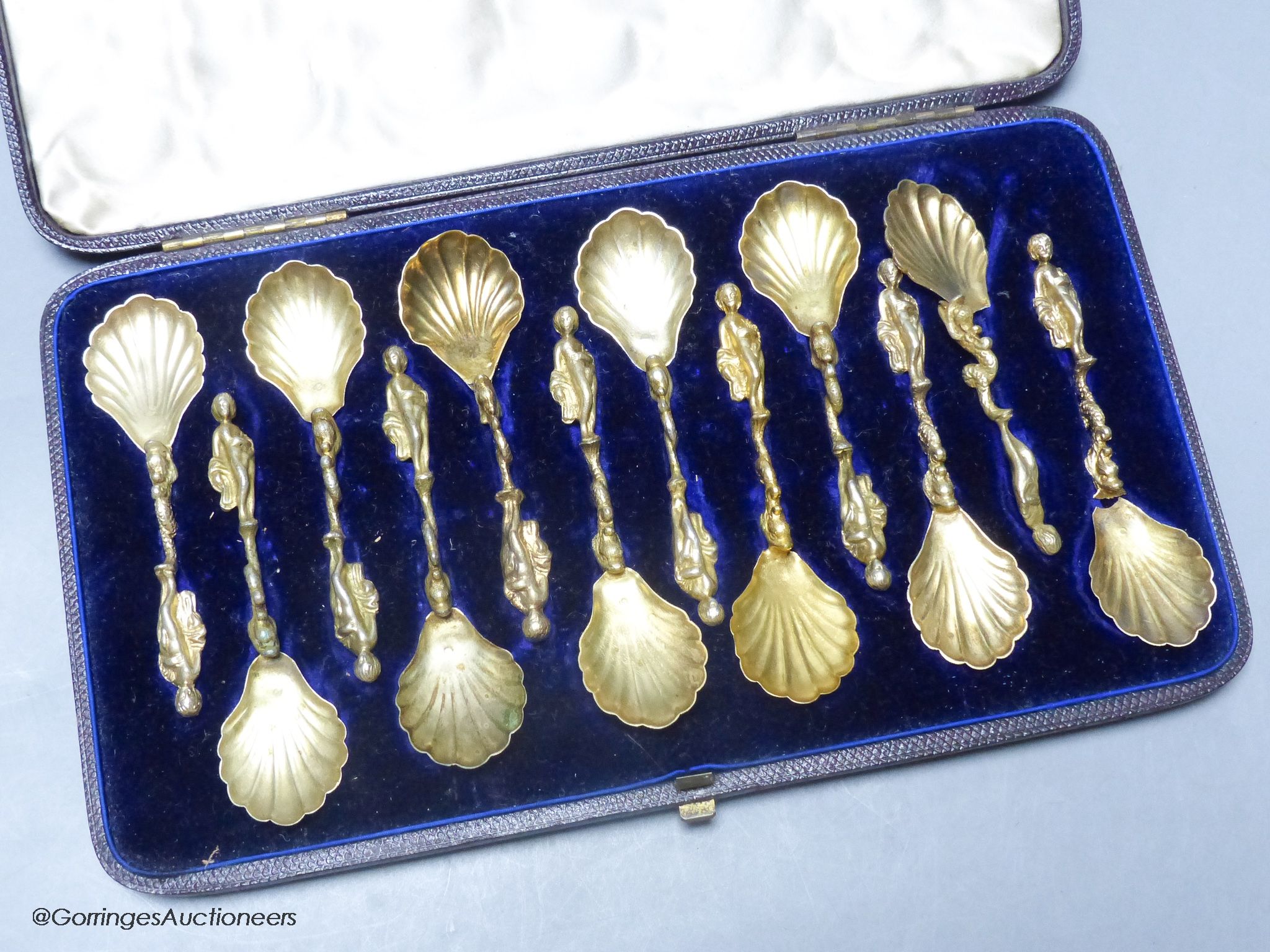 A 19th century cased set of twelve Italian? gilt white metal spoons, with figural and dolphin stem and shell bowls (two broken)